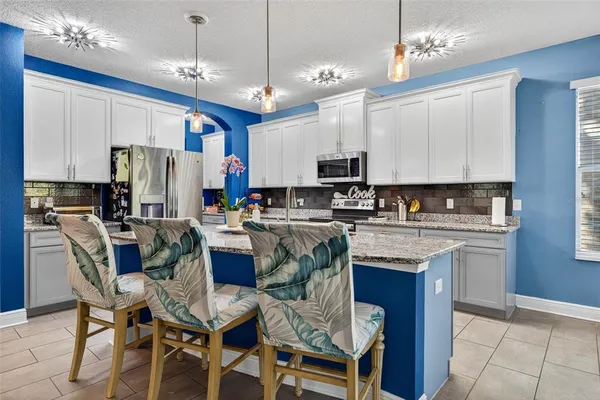 a kitchen with stainless steel appliances granite countertop a stove top oven a refrigerator a sink dishwasher a dining table and chairs with wooden floor