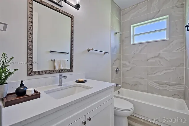 a bathroom with a granite countertop sink a toilet a mirror and shower