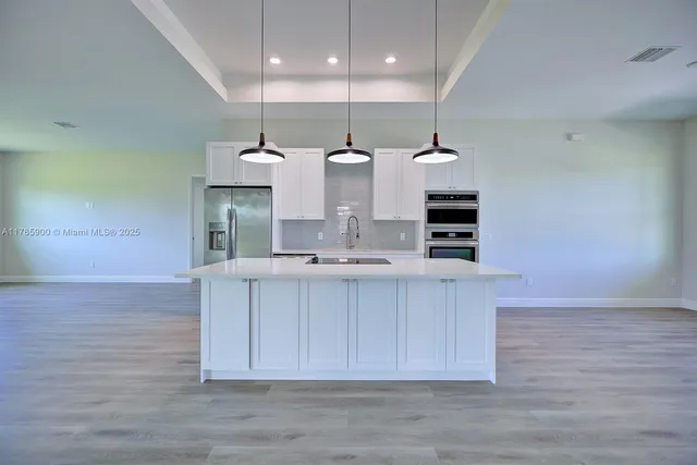 a view of a kitchen with kitchen island a sink wooden floor and a large window
