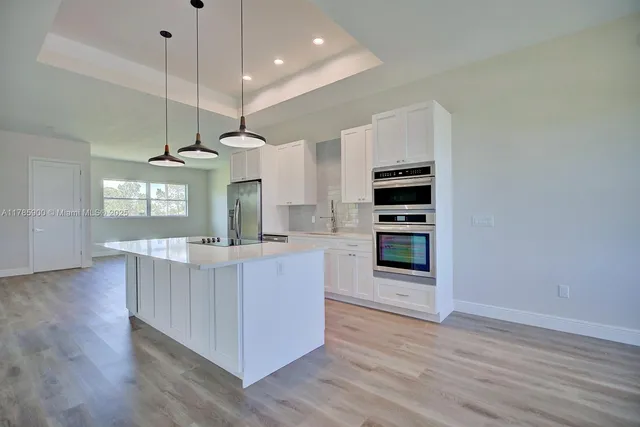 a kitchen with kitchen island white cabinets and stainless steel appliances
