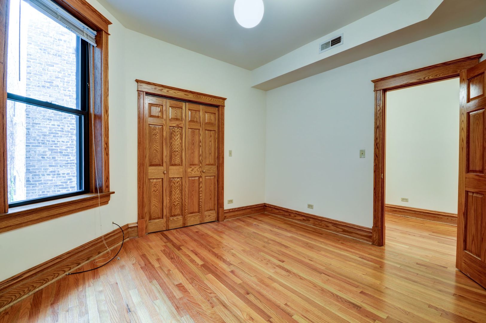 3722 North Fremont Street, Unit 2 Chicago, IL 60613 - Photo 10 of 16 a view of an empty room with wooden floor and a window