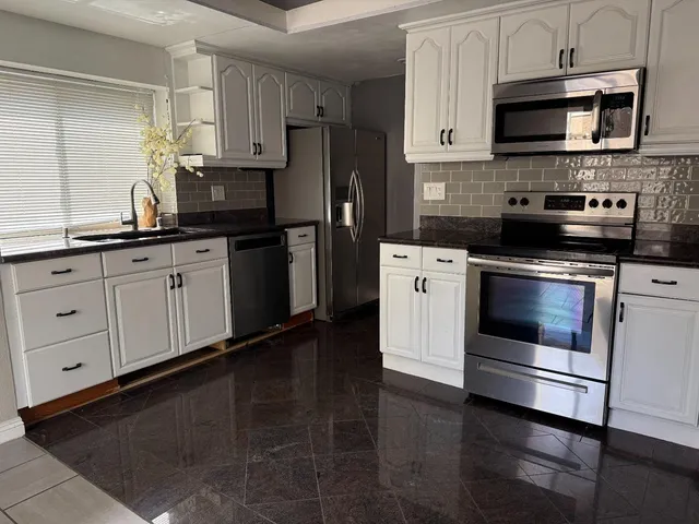 a kitchen with stainless steel appliances a stove microwave and sink