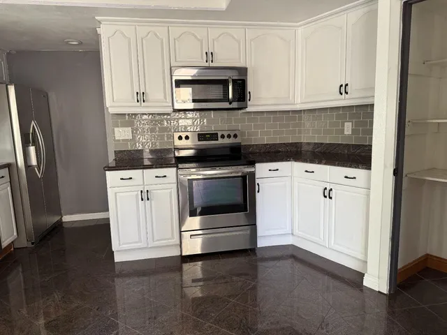 a kitchen with granite countertop a stove and a refrigerator