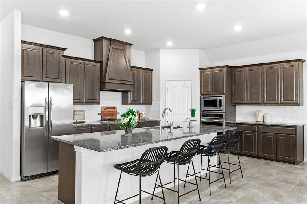 3100 Rademaker Drive Heath, TX 75126 - Photo 8 of 26 a kitchen with granite countertop a sink refrigerator and cabinets