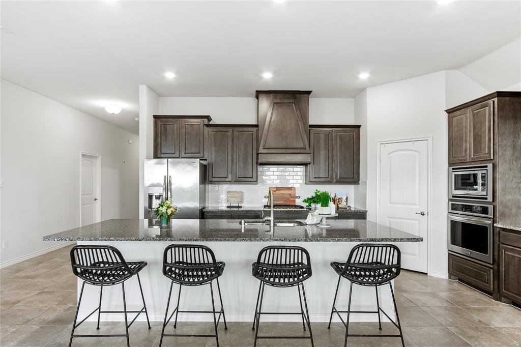 3100 Rademaker Drive Heath, TX 75126 - Photo 9 of 26 a kitchen with stainless steel appliances a dining table chairs stove and refrigerator