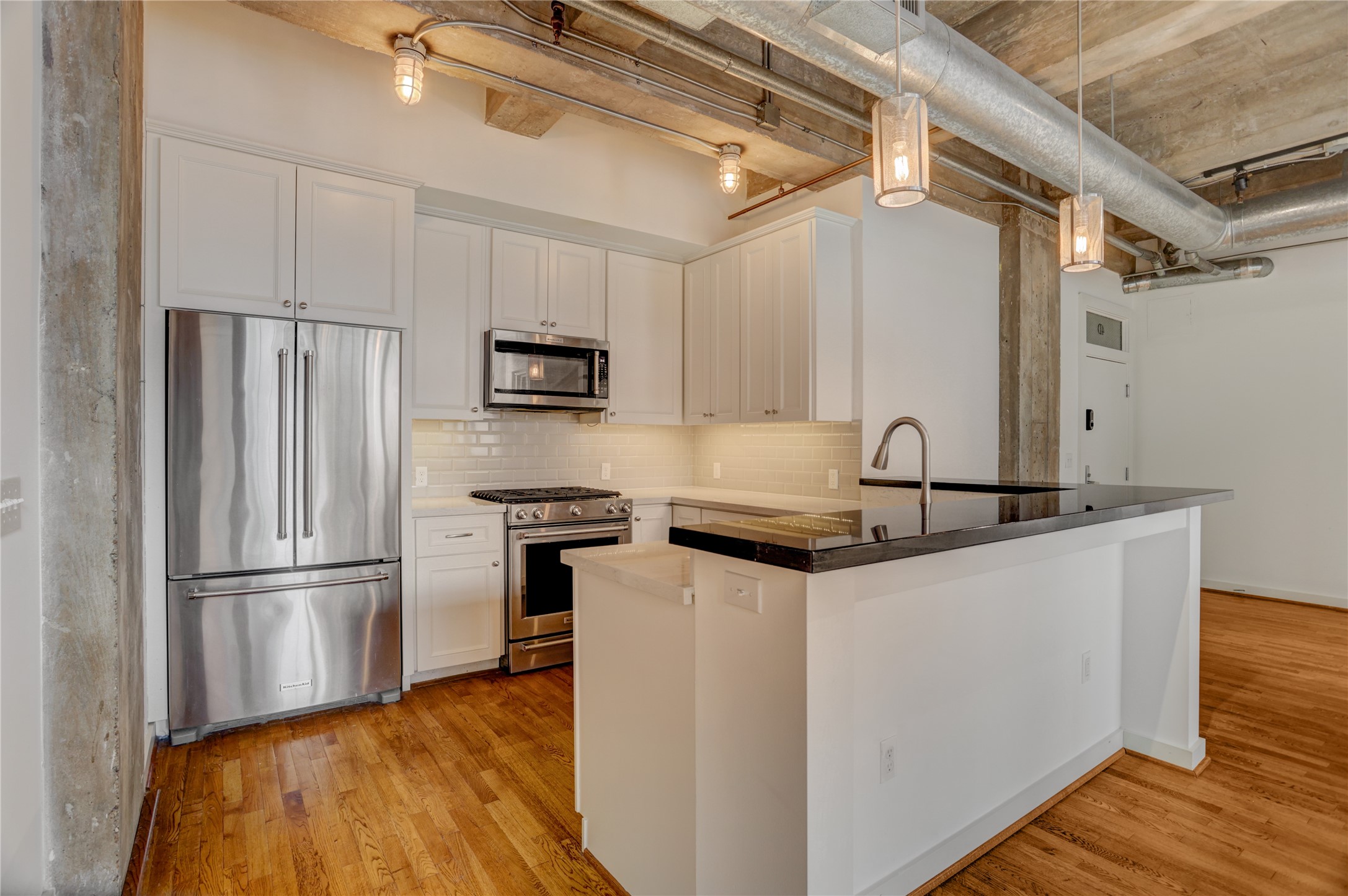 204 Travis Street, Unit 4D Houston, TX 77002 - Photo 4 of 22 a kitchen with stainless steel appliances granite countertop a refrigerator a stove a sink and a microwave