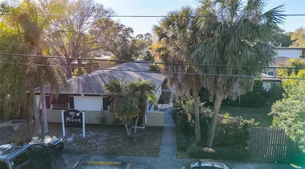 a backyard of a house with table and chairs potted plants and large tree