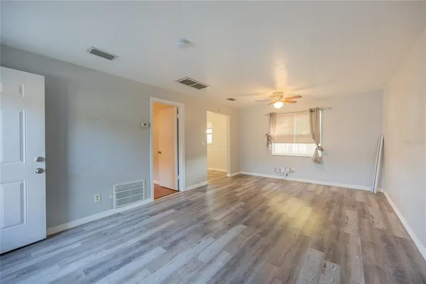 an empty room with wooden floor and windows