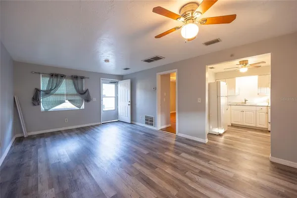 a view of an empty room with window and wooden floor