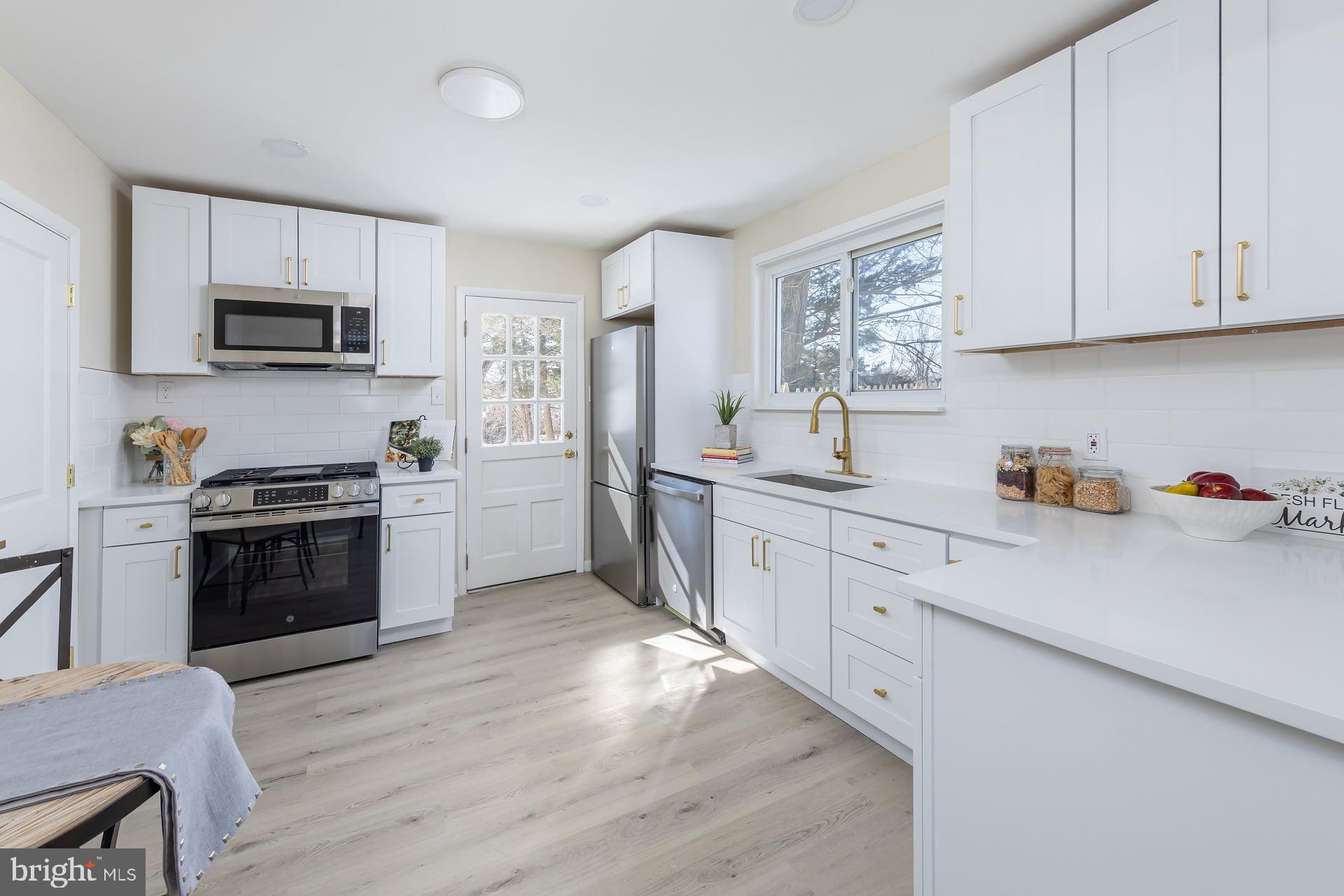 1117 Monmouth Road Deptford, NJ 08096 - Photo 8 of 18 a kitchen with stainless steel appliances granite countertop white cabinets a sink a stove a microwave and wooden floors