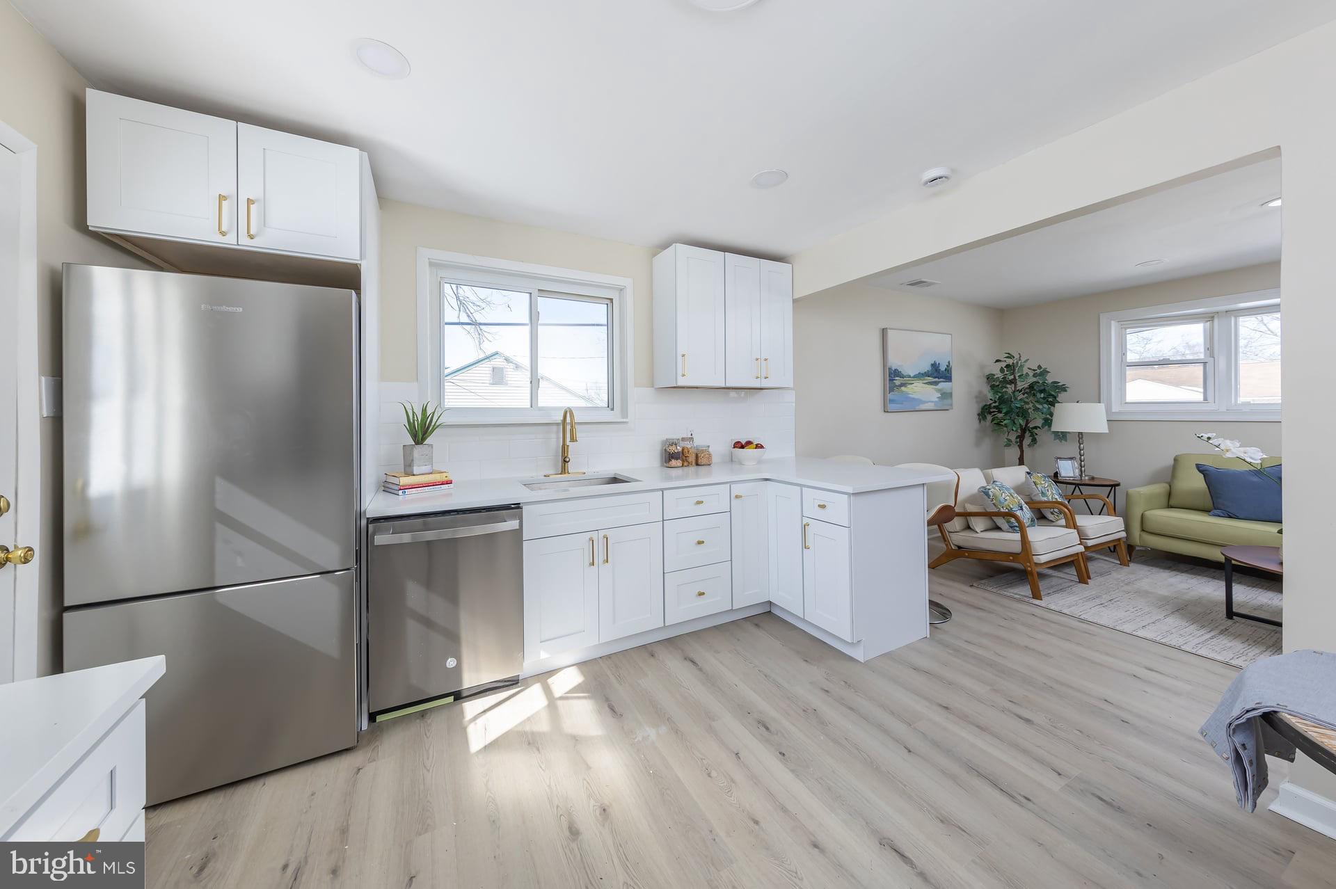 1117 Monmouth Road Deptford, NJ 08096 - Photo 9 of 18 a kitchen with a refrigerator a white stove top oven a sink dishwasher and white cabinets with wooden floor