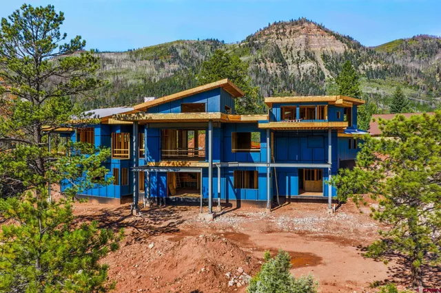a front view of a house with a yard and large trees