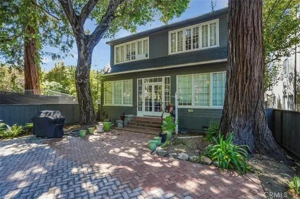 a view of a house with a yard and large tree
