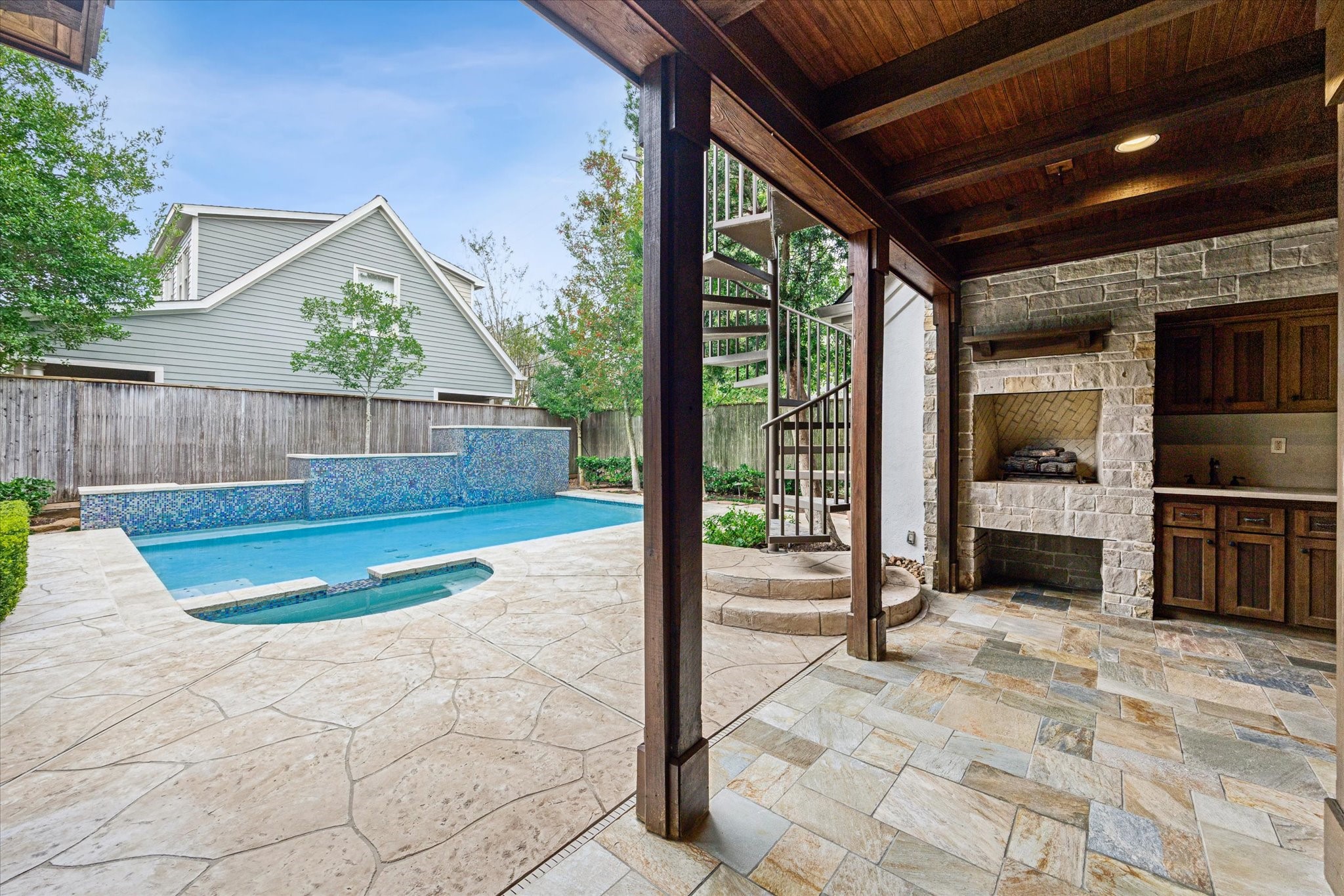 3715 Garnet Street Houston, TX 77005 - Photo 44 of 50 A gas fireplace adds to the ambiance of the outside patio space, while the expansive decking surrounds the pool. The spiral staircase leads to the private quarters above the garage.
