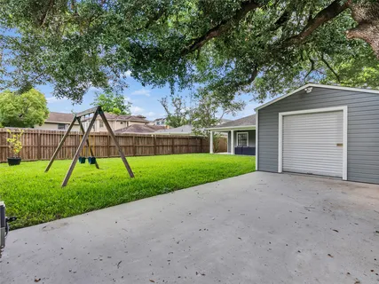 a view of a house with a yard and a large tree