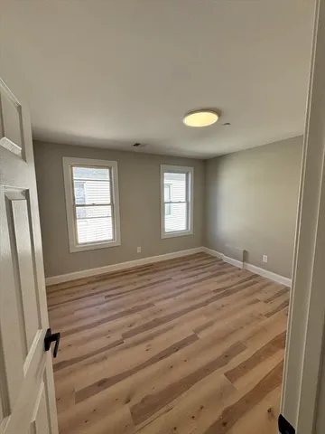 a view of empty room with window and wooden floor