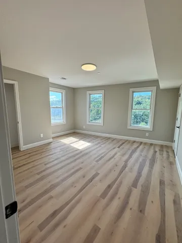 a view of empty room with window and wooden floor