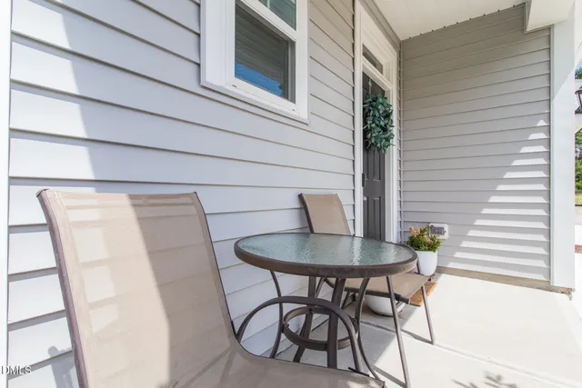 a balcony with table and chairs and a potted plant