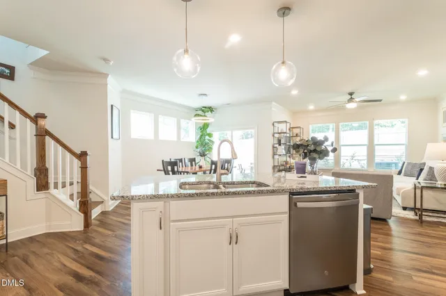 a kitchen with stainless steel appliances kitchen island a chandelier dining table chairs and wooden floor