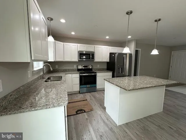 a kitchen with stainless steel appliances granite countertop a refrigerator a stove a sink and a microwave