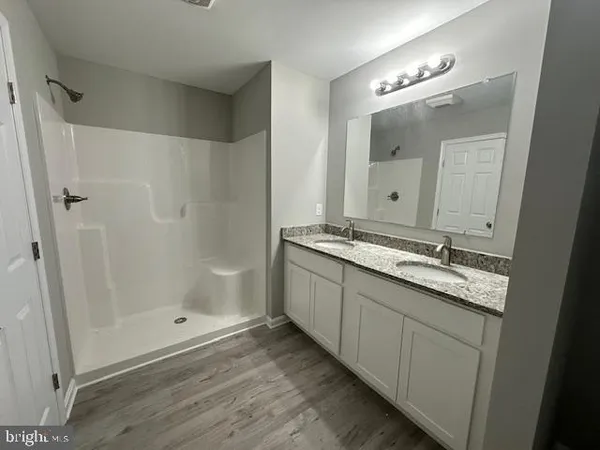 a bathroom with a granite countertop sink a mirror and a shower