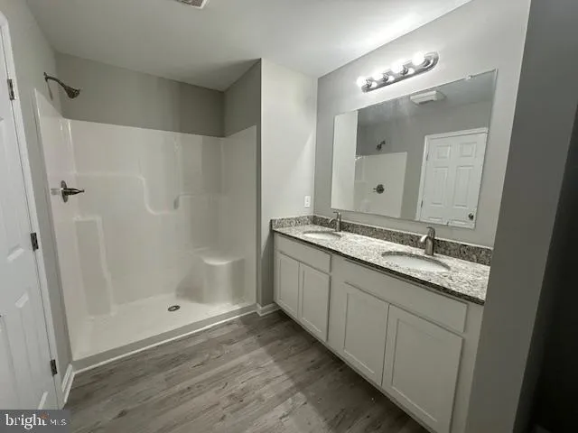 a bathroom with a granite countertop sink a mirror and a shower