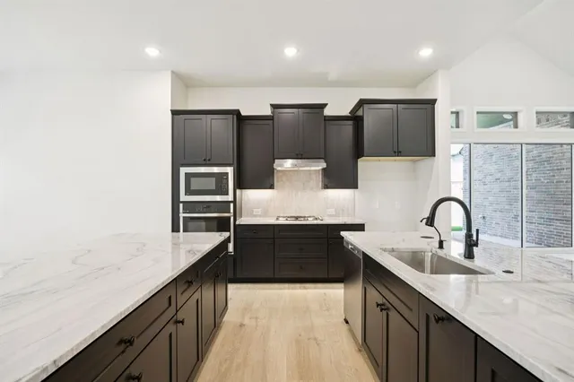 a large kitchen with granite countertop a sink and cabinets