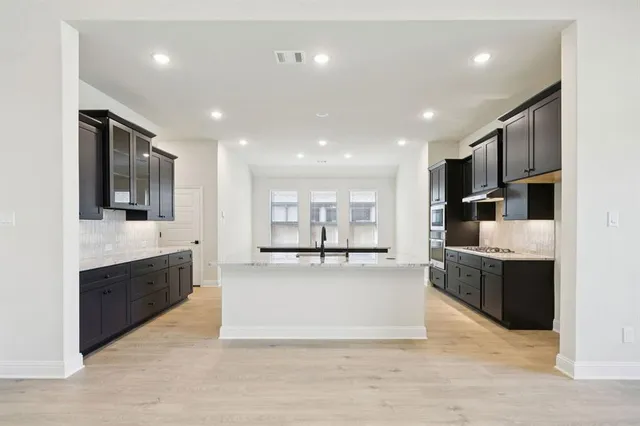 a large white kitchen with kitchen island a sink counter space and stainless steel appliances