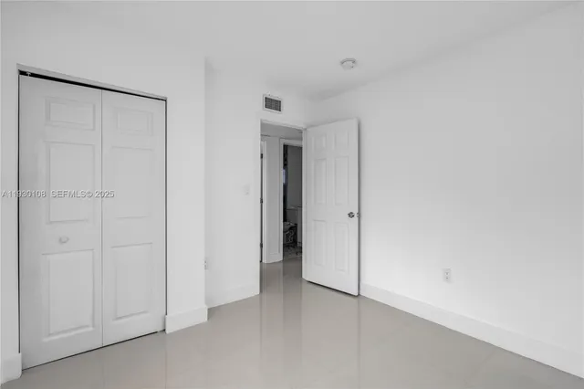 an empty room with stainless steel appliances kitchen island granite countertop a stove and a refrigerator
