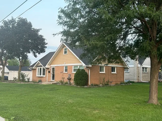 a view of a yard in front of a house with plants and large tree