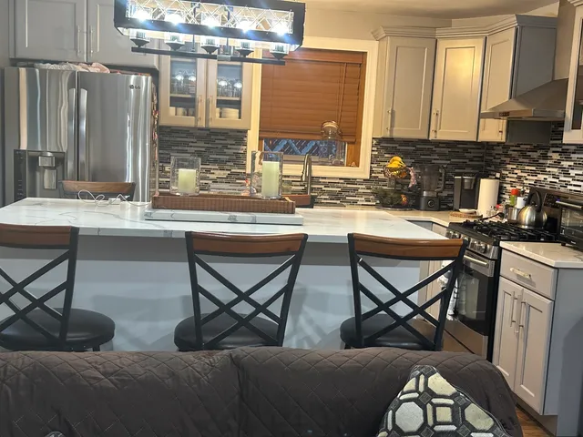 a kitchen with stainless steel appliances granite countertop table chairs and a refrigerator