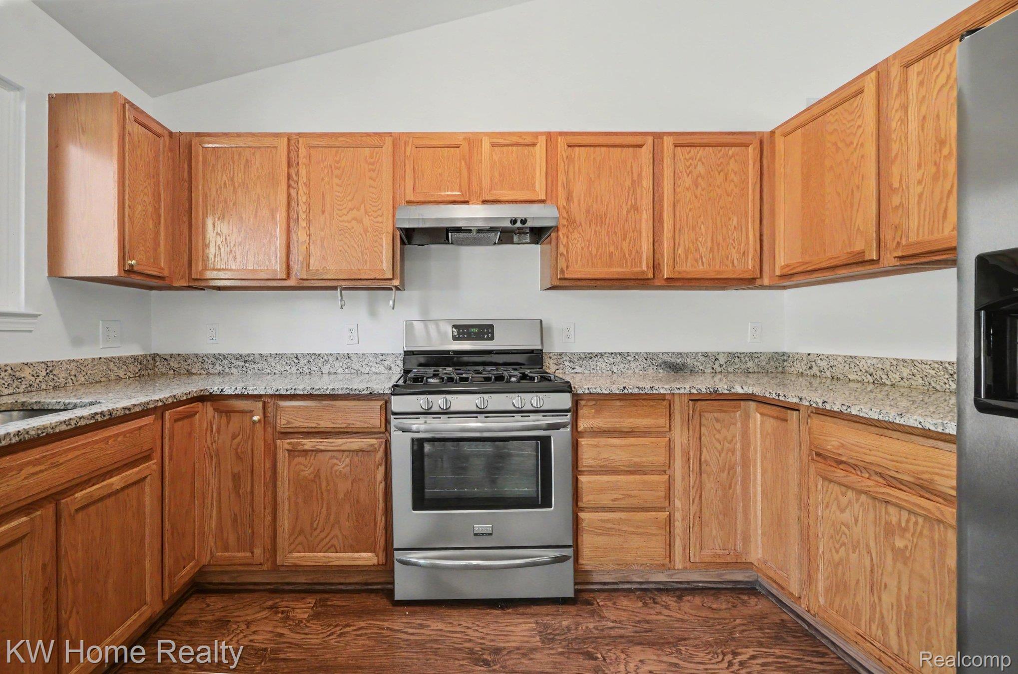2383 East Maple Road Troy, MI 48083 - Photo 6 of 25 Kitchen featuring wood-finish cabinetry, light-toned countertops, and a stainless steel range with a coordinating hood