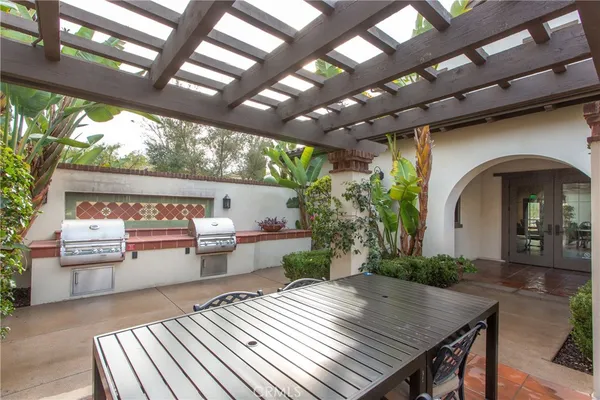 a view of a patio with table and chairs potted plants and floor to ceiling window