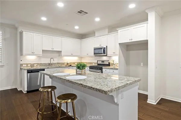 a kitchen with granite countertop white cabinets and refrigerator