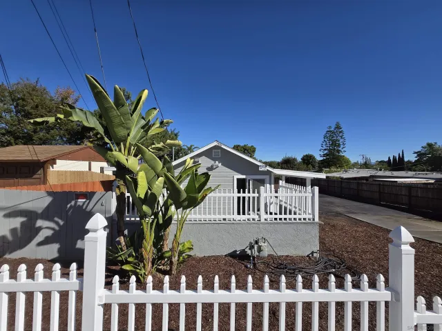 a front view of a house with yard tree and wooden fence