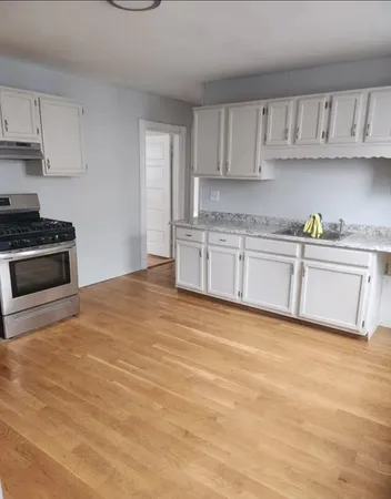 a kitchen with granite countertop a stove a sink and a white cabinets