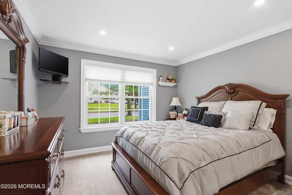 a bedroom with a bed a couch and a flat tv screen on dresser