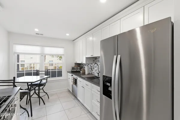 a kitchen with stainless steel appliances a refrigerator a table and chairs