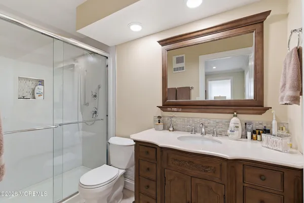 a bathroom with a shower sink vanity mirror and toilet