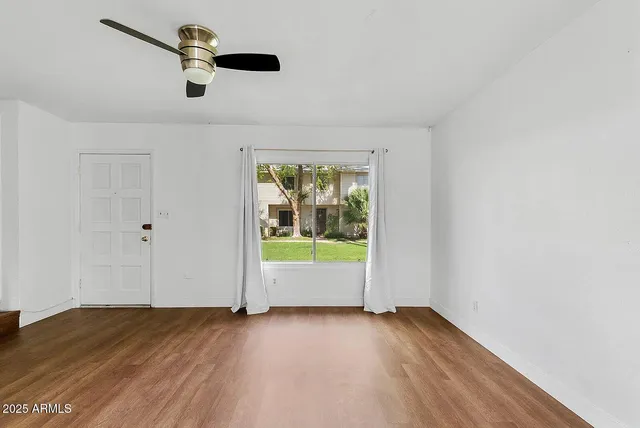 an empty room with wooden floor and windows