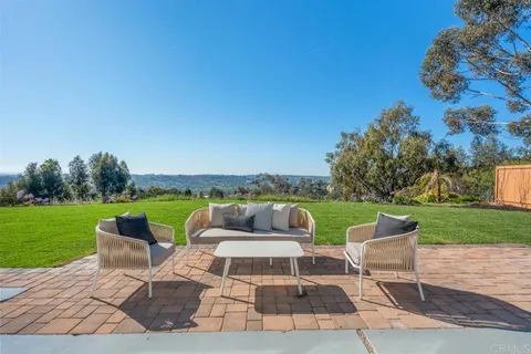 a view of a patio with couches potted plants and a big yard