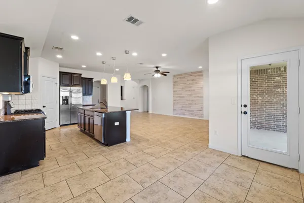 a kitchen with stainless steel appliances kitchen island granite countertop a refrigerator and a sink
