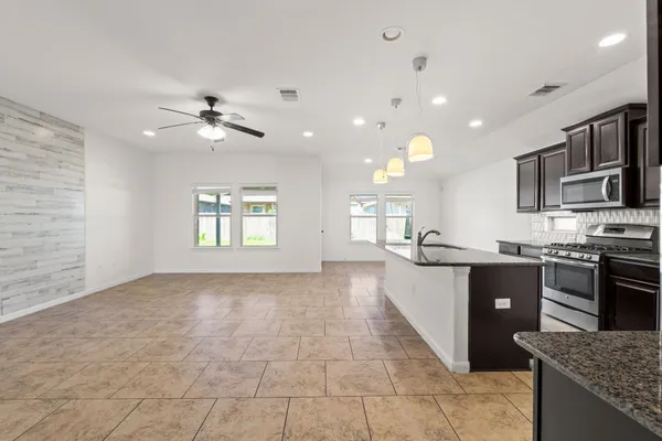 a large kitchen with stainless steel appliances granite countertop a refrigerator a stove a sink and a microwave