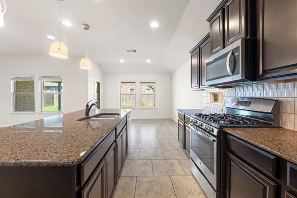 a kitchen with granite countertop stainless steel appliances and wooden floor