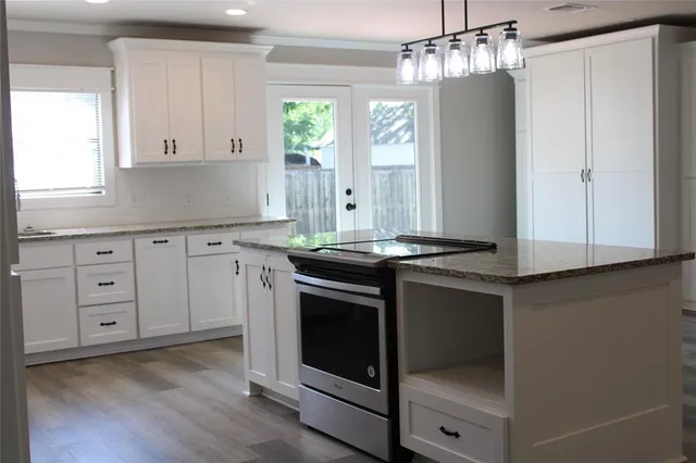 a kitchen with granite countertop white cabinets and stainless steel appliances