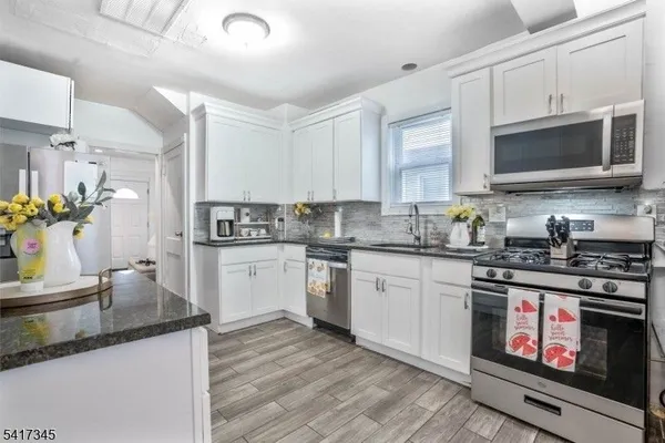 a kitchen with stainless steel appliances granite countertop a stove a sink and a microwave