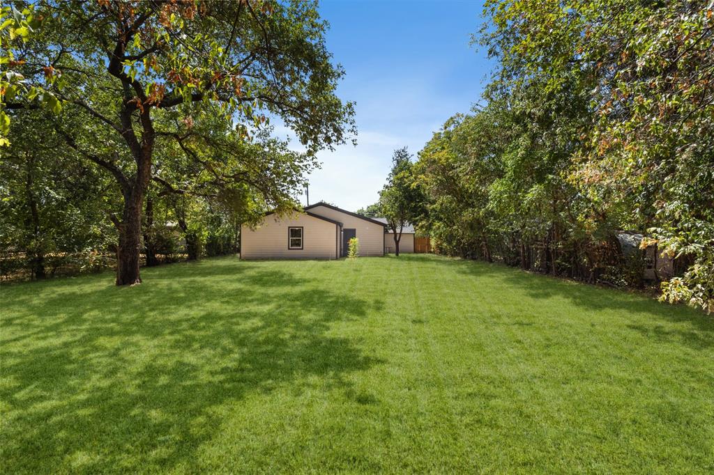 513 East Union Bower Road Irving, TX 75061 - Photo 30 of 34 Expansive green lawn with mature trees and a single-story structure with a gabled roof