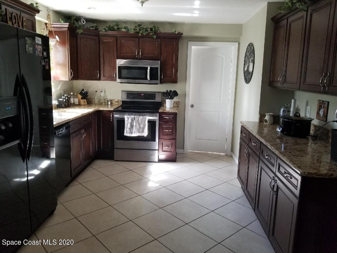 2173 Fatzler Road Melbourne, FL 32935 - Photo 3 of 13 a kitchen with stainless steel appliances granite countertop a refrigerator and a stove top oven