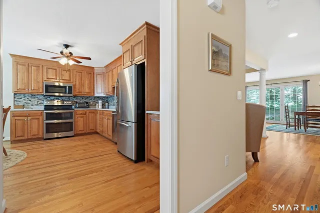 a kitchen with stainless steel appliances granite countertop a stove a refrigerator a microwave a dining table and chairs with wooden floor