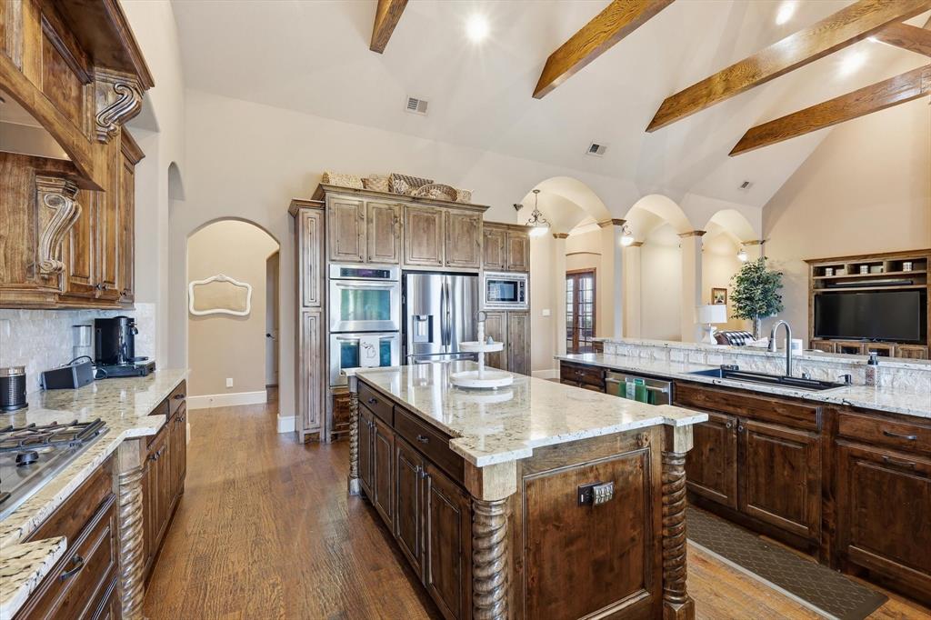 406 Spurgin Road Lucas, TX 75002 - Photo 10 of 39 Kitchen with vaulted ceiling, light stone countertops, arched walkways, dark wood-style flooring, and stainless steel appliances